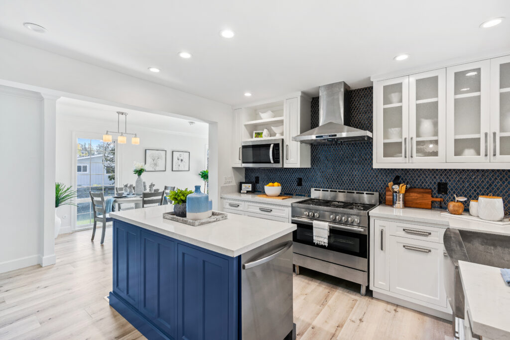 A kitchen with white cabinets and blue island.